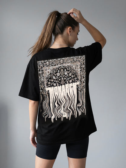Person wearing a black t-shirt with a white graphic "MONARCH" design on the back against a gray background