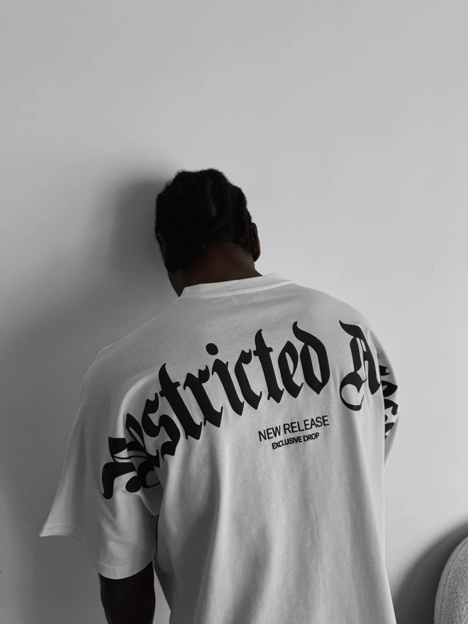 Person wearing a white t-shirt with "Restricted Access" design on the back against a plain background