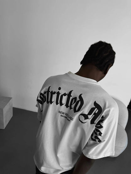 Person wearing a white tshirt with "Restricted Access" design on the back, standing indoor.