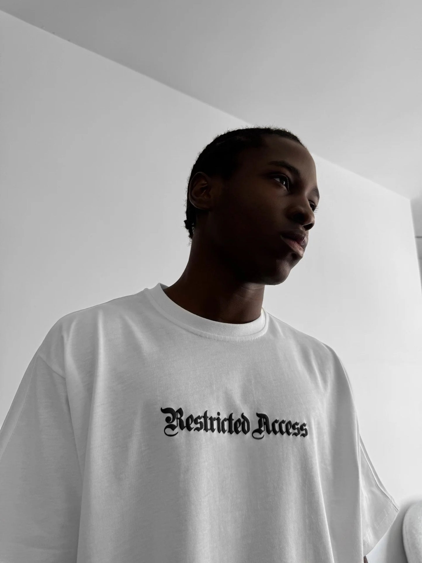 Person wearing a white shirt with 'Restricted Access' text against a plain background