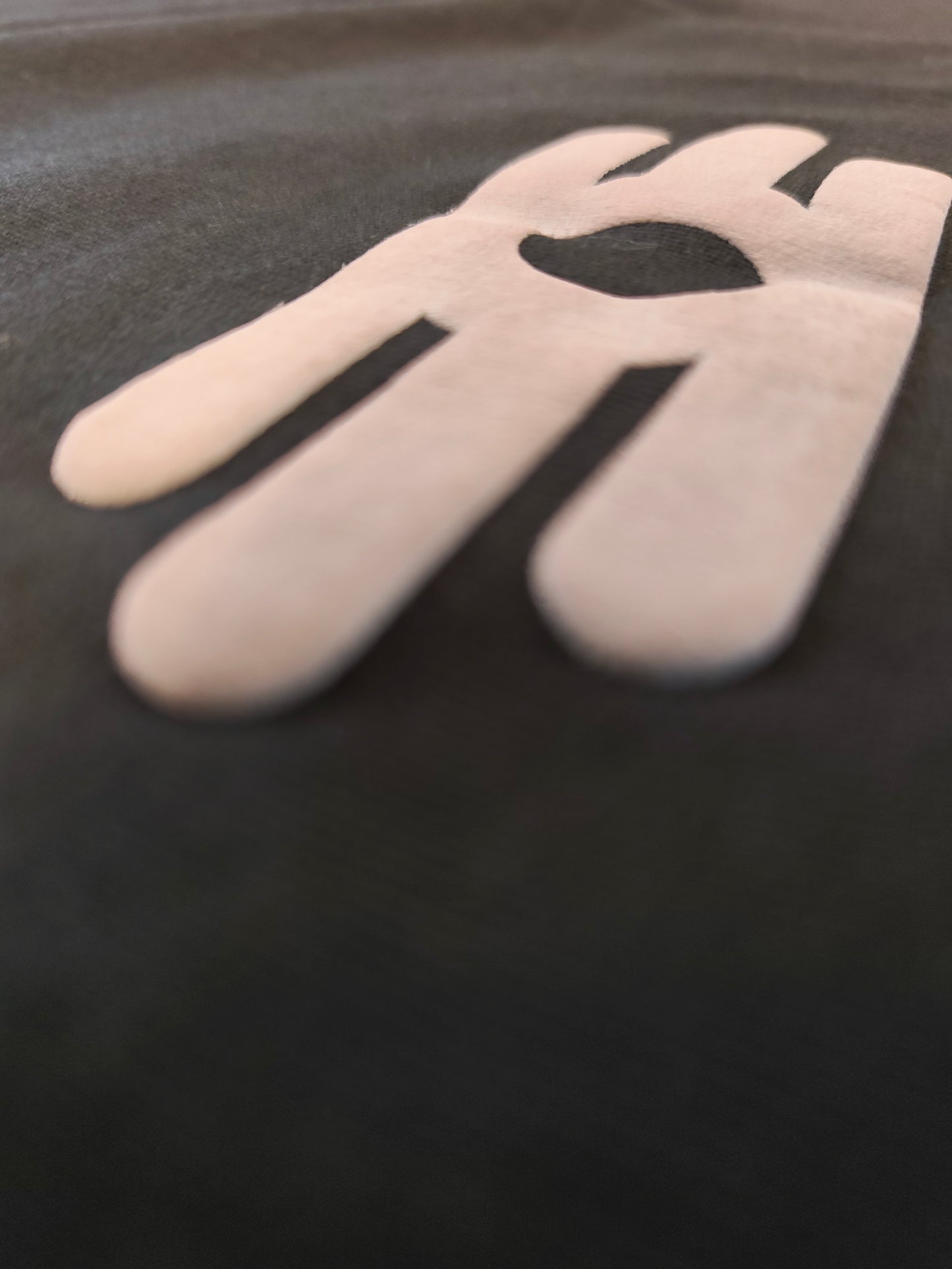 A close-up shot of a black fabric surface featuring large, raised graphics.