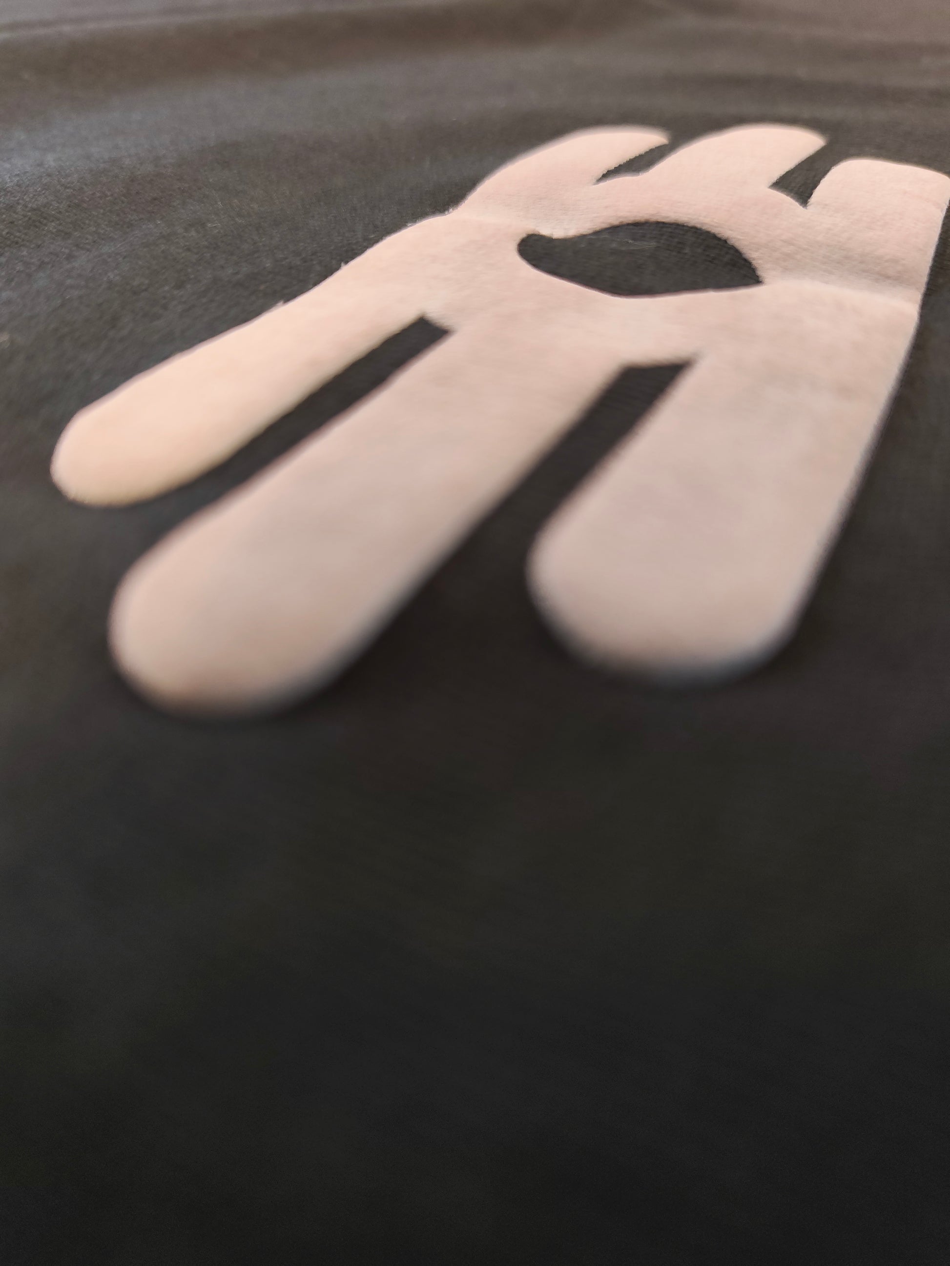 A close-up shot of a black fabric surface featuring large, raised graphics.
