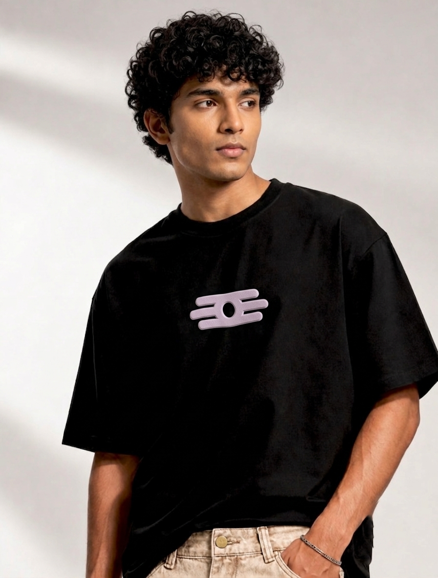 A man wearing a black crewneck t-shirt with a small light pink graphic logo on the center chest.